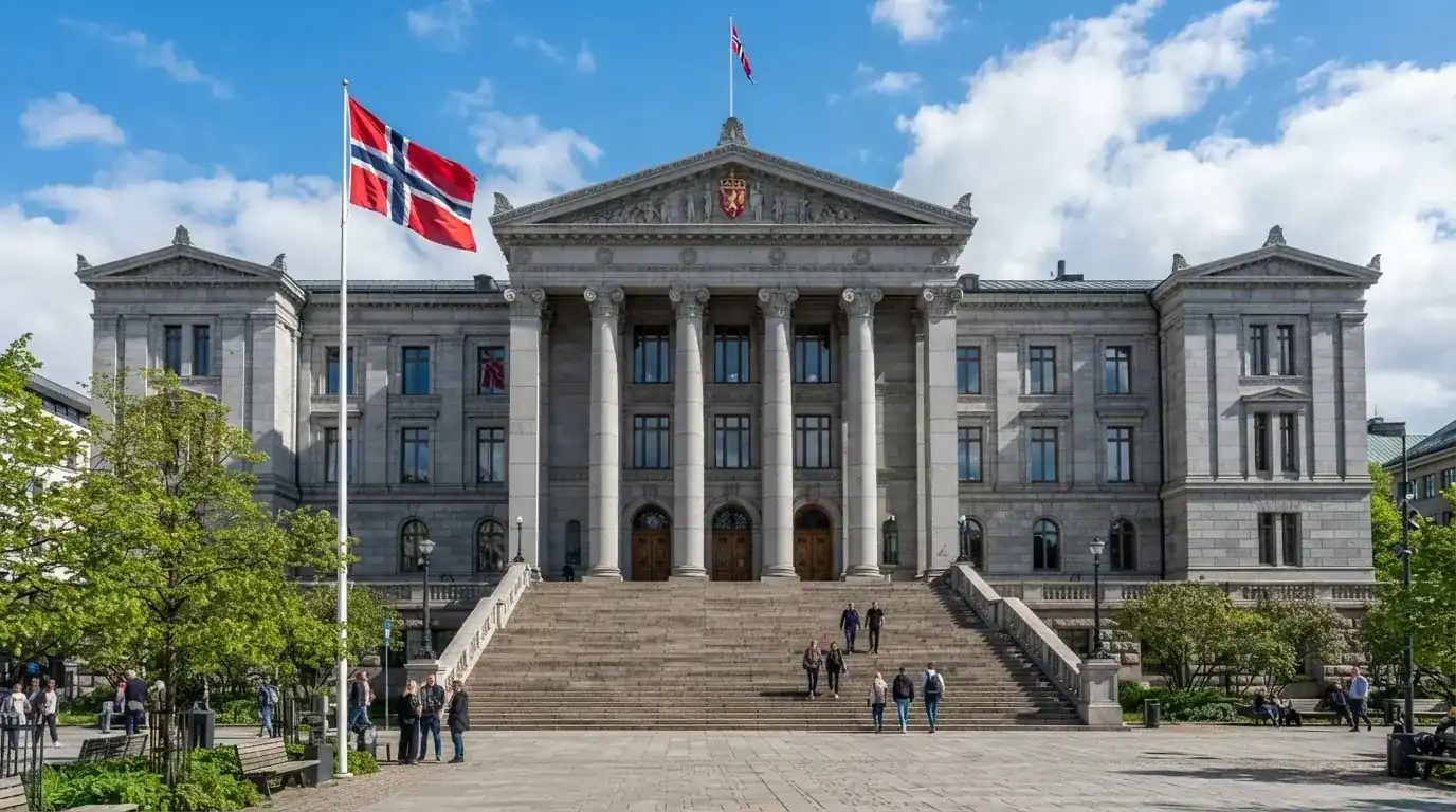 Fasade av en stor offentlig bygning i Oslo med brede trapper og et norsk flagg i vinden under klar himmel