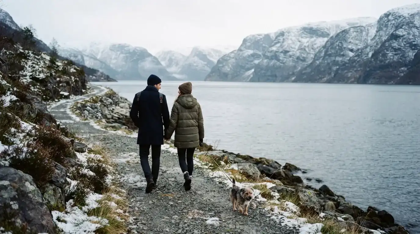 Ungt par går tur ved fjorden med hund en kald dag